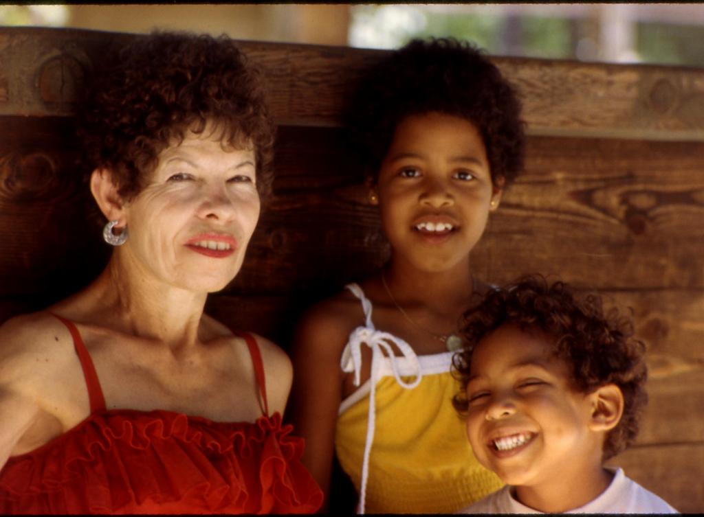 Older olive-complected woman and two darker skinned children, all dressed for summer.